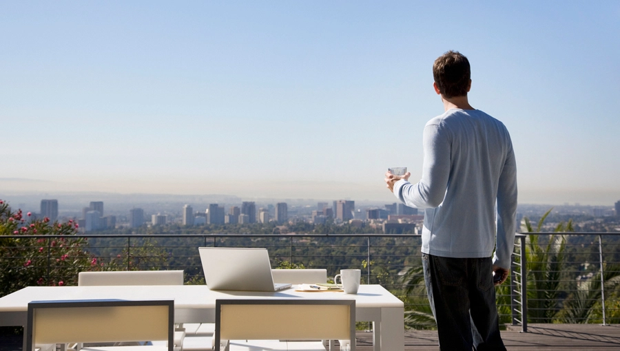 Man on a balcony with laptop.