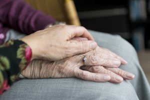 financial plan closeup of adult child holding elderly parent's hand