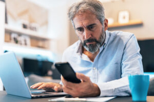 cybersecurity-investment-scams-mature-man-looking-phone